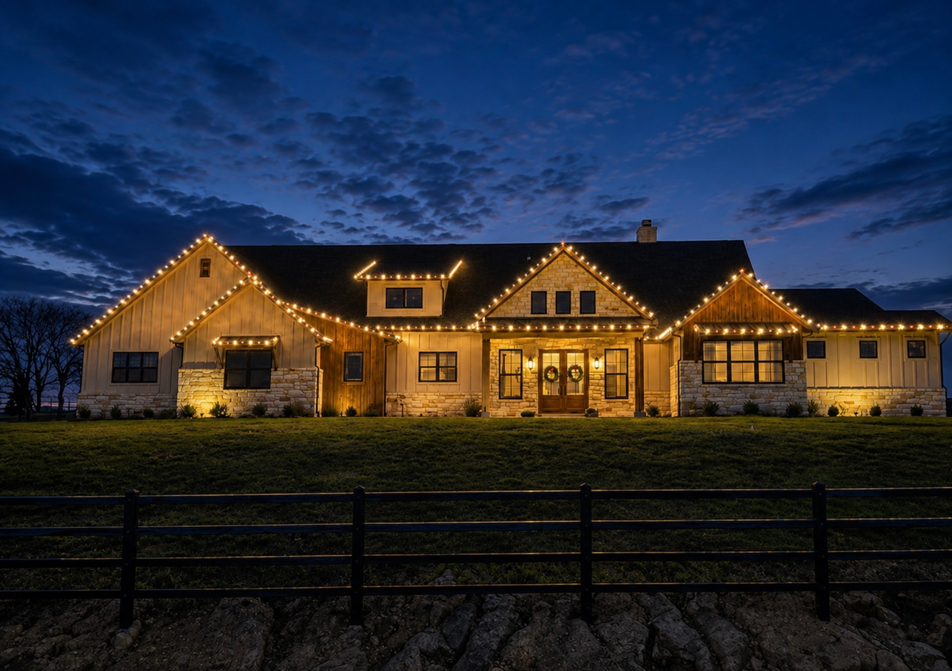 Warm white Christmas lights outlining a North Texas farmhouse at twilight