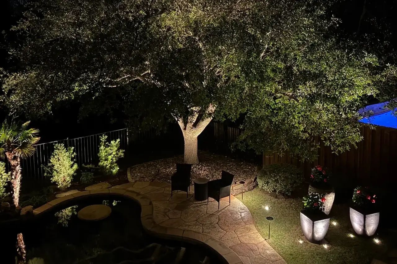 Landscape lighting on a mature oak tree over a backyard water feature
