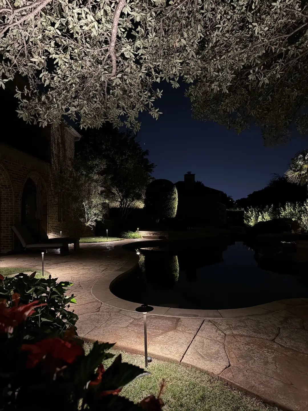 Landscape lighting surrounding a pool at night with pathway lights